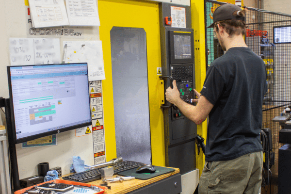 A machinist preparing a CNC machine for production, adjusting controls and tooling during the setup process to ensure accurate and efficient machining.
